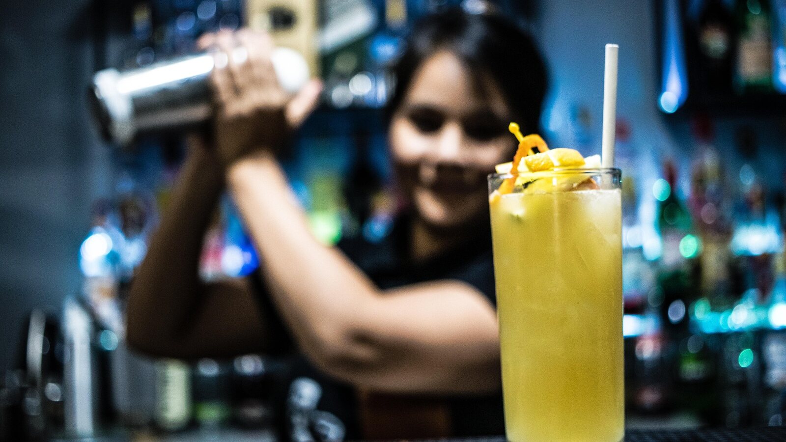 A bartender shakes a cocktail behind the bar